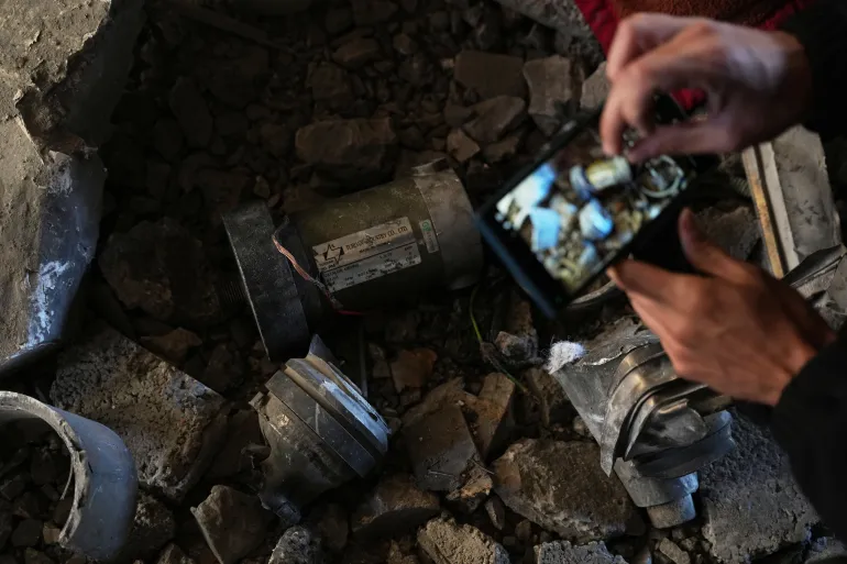 Palestinian examines missile remains from Israeli airstrike in Deir al-Balah.