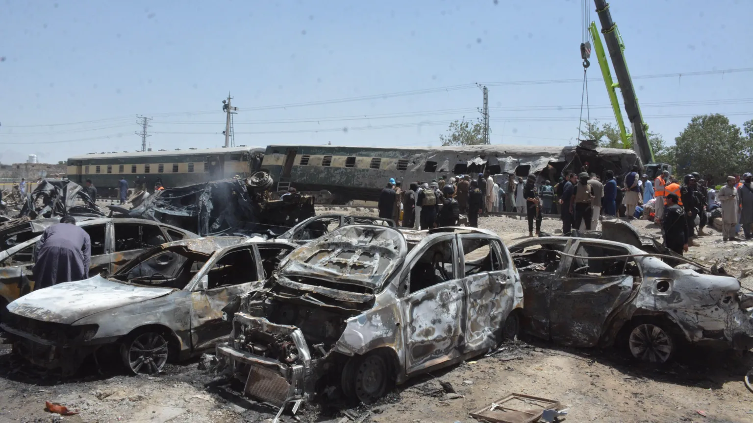 Charred vehicles and a derailed train at the blast site in Quetta, Pakistan, where at least 24 people were killed.