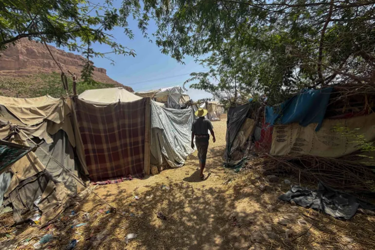 A man walks between makeshift tents constructed from tarpaulins and scrap materials at an IDP camp in eastern Yemen.