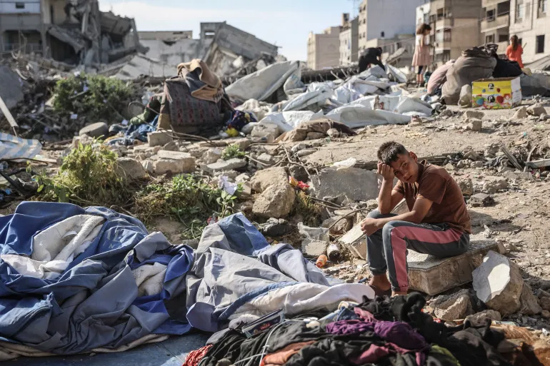 Palestinian boy sits amid ruins of overnight Israeli military strike that killed dozens during Eid holiday period.