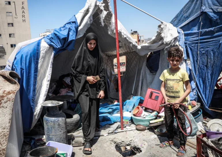 Widad al-Husari inspects her tent among the ruins after an Israeli strike destroyed the building sheltering her family.