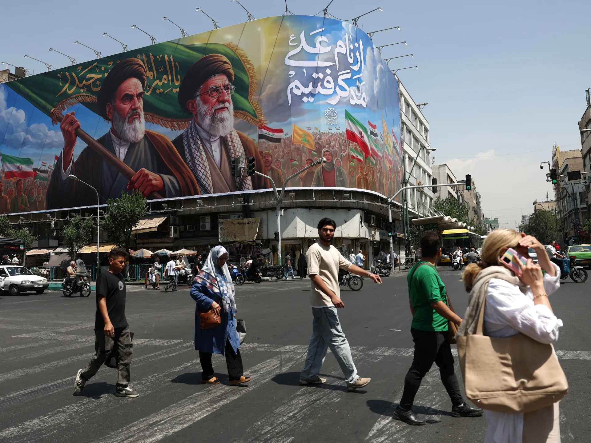 People walk past a billboard depicting the late supreme leaders, Ruhollah Khomeini and Ali Khamenei, on a street in Tehran, Iran, on June 6, 2026 [Majid Asgaripour/WANA via Reuters]