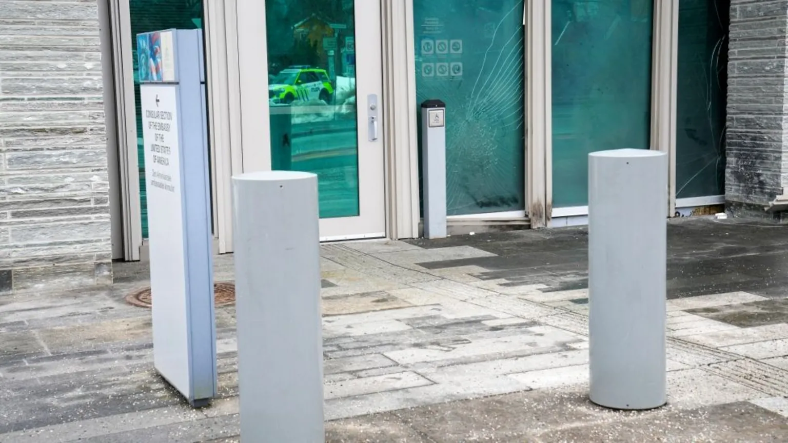 Burn marks and shattered glass doors visible at the US Embassy following Sunday's incendiary device explosion.