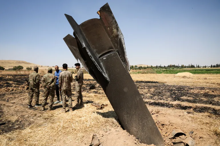 Members of a military engineering team stand beside an Iranian missile, according to local authorities, that fell in the countryside near Damascus, Syria, on June 9, 2026 [Khalil Ashawi/Reuters]