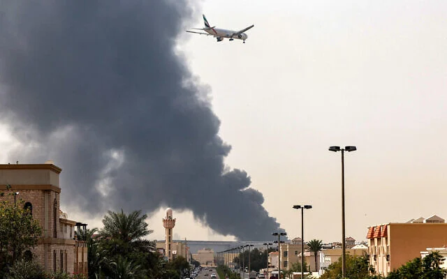 File: An Emirates aircraft prepares for landing as a smoke plume rises from an ongoing fire near Dubai International Airport in Dubai on March 16, 2026 (AFP)