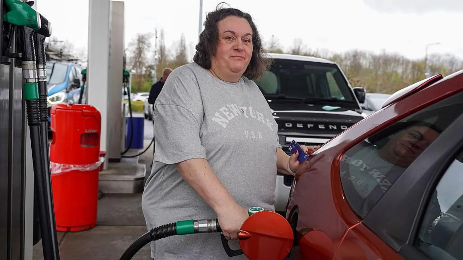 Getty Images A woman looks at the camera as she fills herred car at a petrol station in Derby
