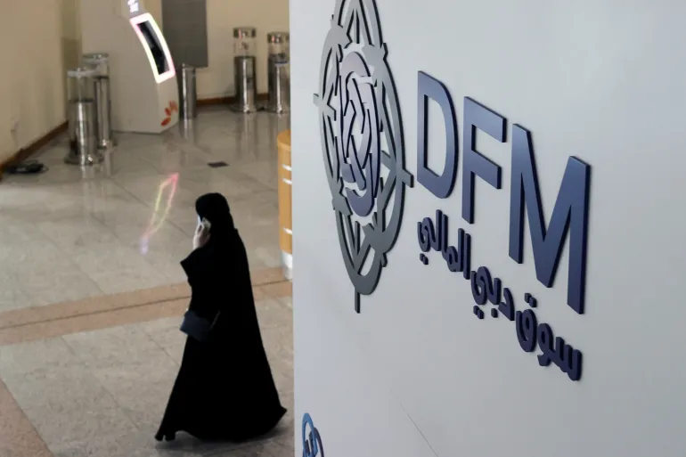 A woman walks through Dubai Financial Market during period of significant market volatility affecting Gulf economies.
