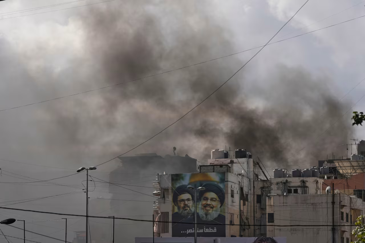Portraits of Hezbollah's late leaders Hassan Nasrallah, right, and his cousin, Hashem Safieddine, are seen, as smoke rises following an Israeli airstrike in Dahiyeh, Beirut's southern suburbs, Lebanon on Monday.
Hassan Ammar/AP