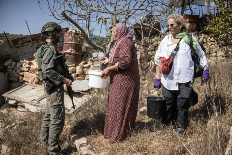 An Israeli soldier confronts Palestinians during olive harvest near the West Bank settlement of Elazar.