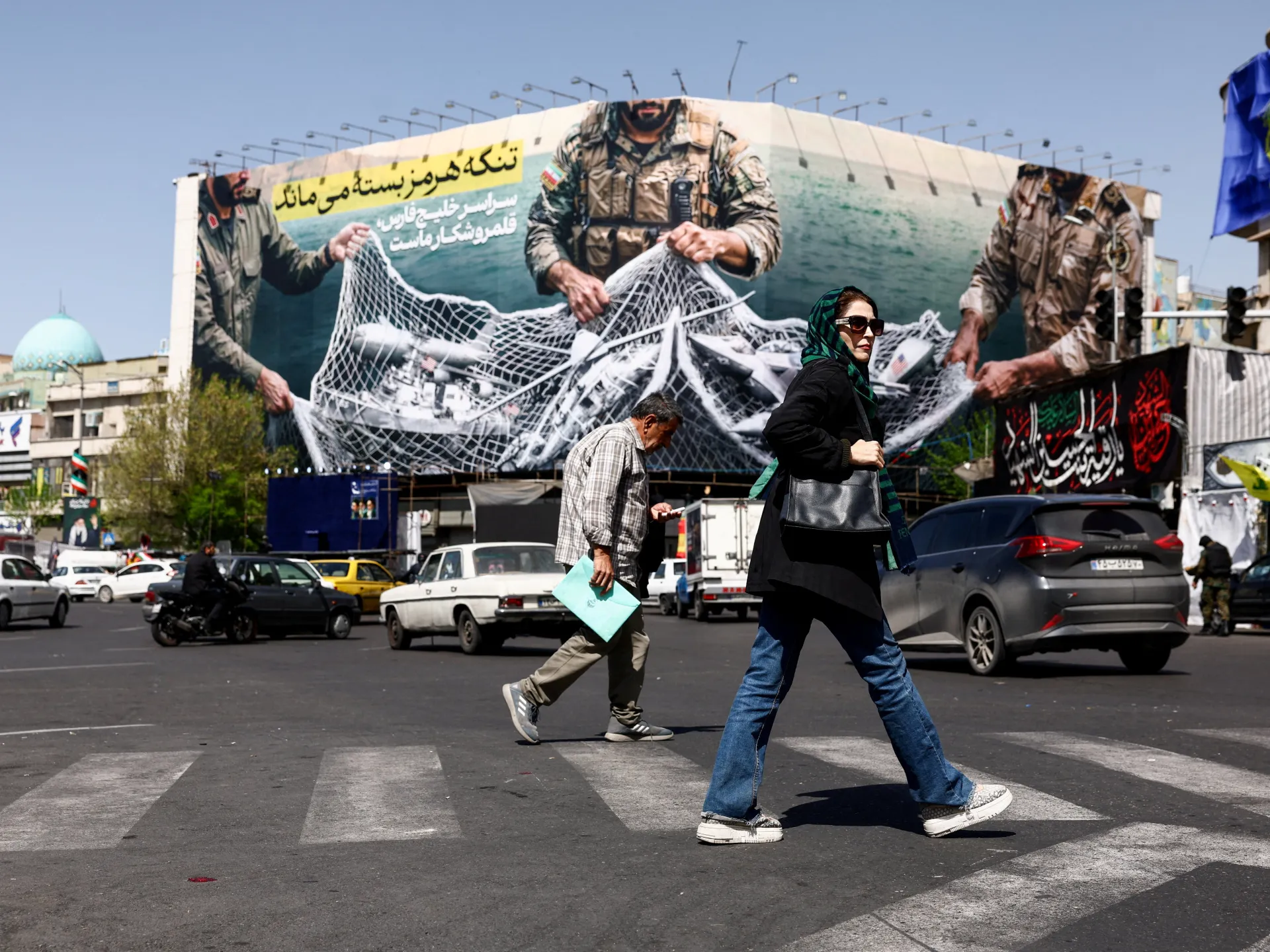 People walk on a street near an anti-US billboard, amid the US-Israel war on Iran, in Tehran, Iran, April 5, 2026 [Majid Asgaripour/WANA (West Asia News Agency) via Reuters]