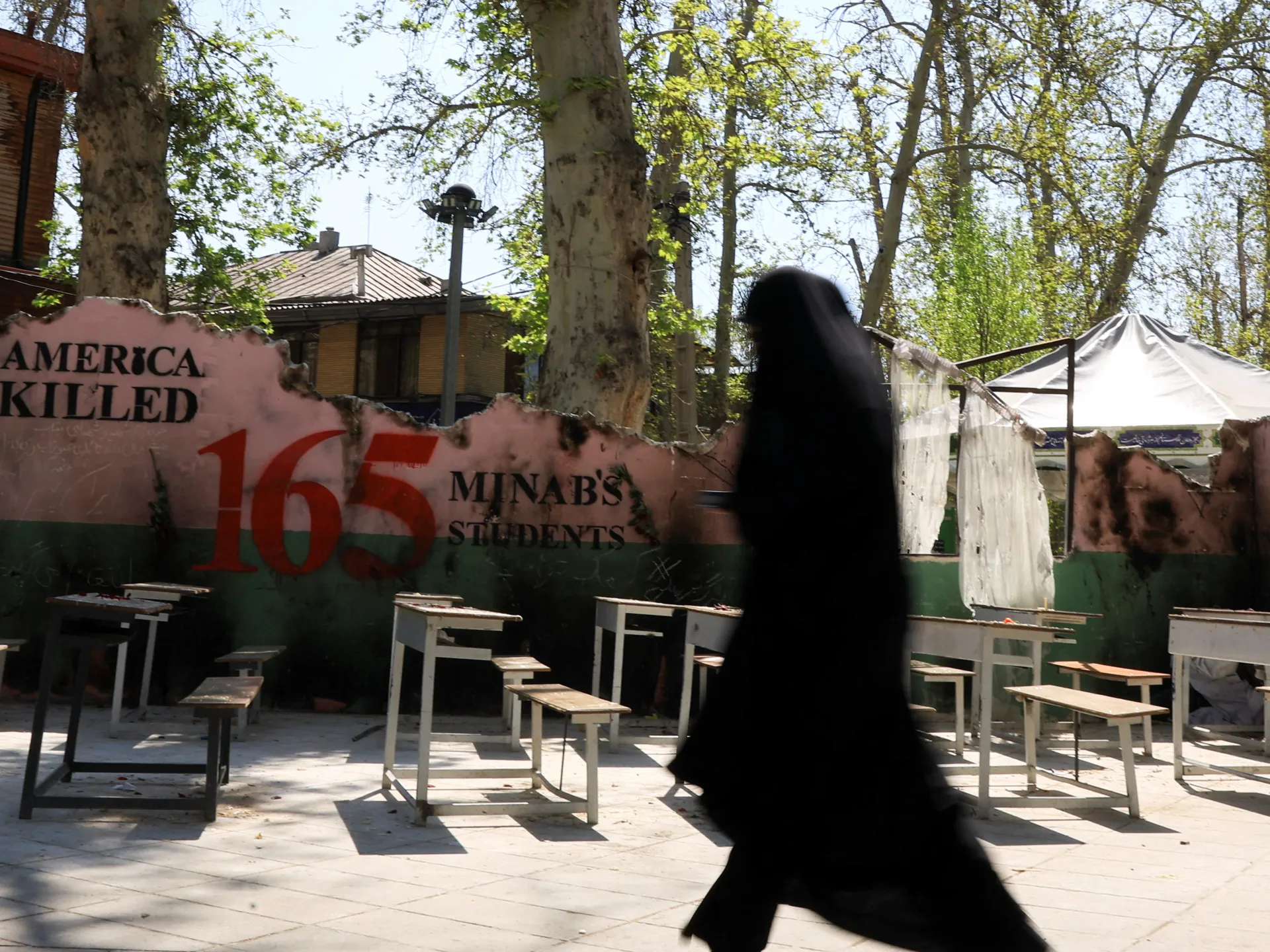 An Iranian woman walks past a monument for schoolchildren who were killed in a strike on a girls' primary school in Minab, southern Iran, amid a ceasefire between the US and Iran, in Tehran, Iran, April 15, 2026. [Thaier Al Sudani/Reuters]