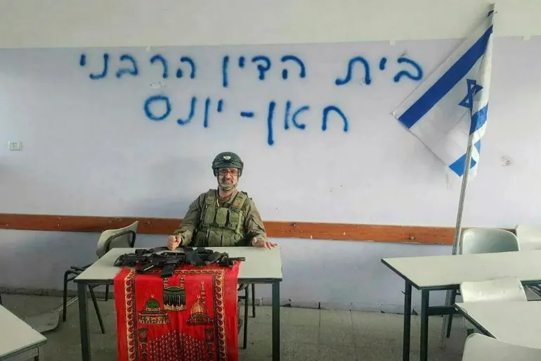 Rabbi Avraham Zarbiv stands in Gaza in December 2023 near graffiti reading 'The Rabbinical Court of Khan Younis.'