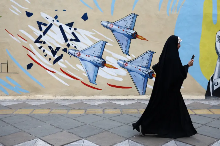 Tehran resident walks past anti-Israeli mural as US-brokered ceasefire takes effect between Iran and America.