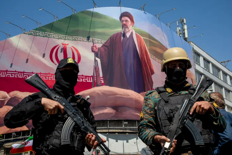 Iranian soldiers stand guard in Tehran beneath a portrait of Supreme Leader Mojtaba Khamenei as tensions escalate.