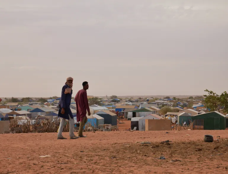 Refugees walk through Mbera camp in Mauritania, hosting hundreds of thousands displaced since 2012 and 2023.