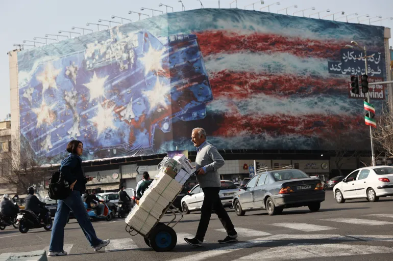 People walk past an anti-US billboard in Tehran, Iran, February 19, 2026 [Majid Asgaripour/West Asia News Agency via Reuters]