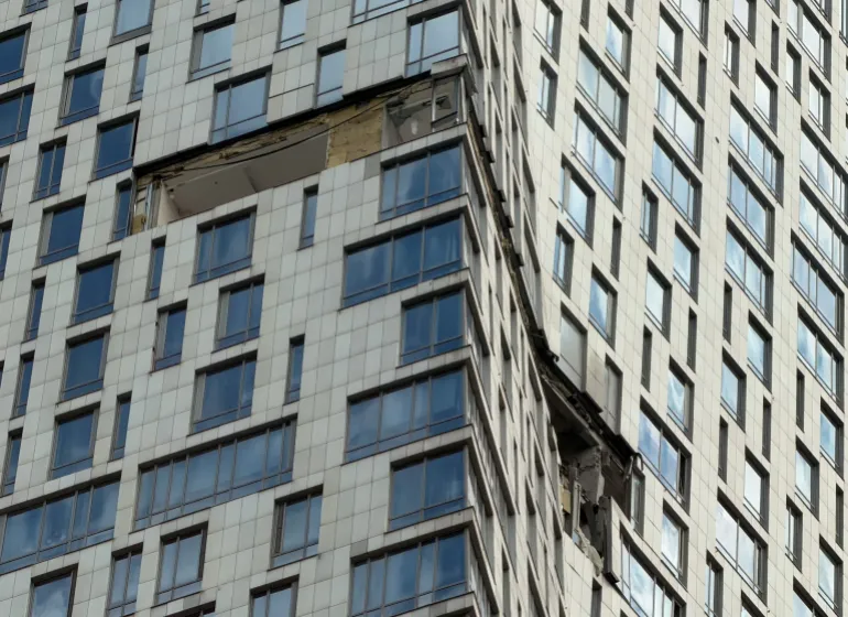Scarred facade of Moscow high-rise building following Ukrainian drone attack on residential area.
