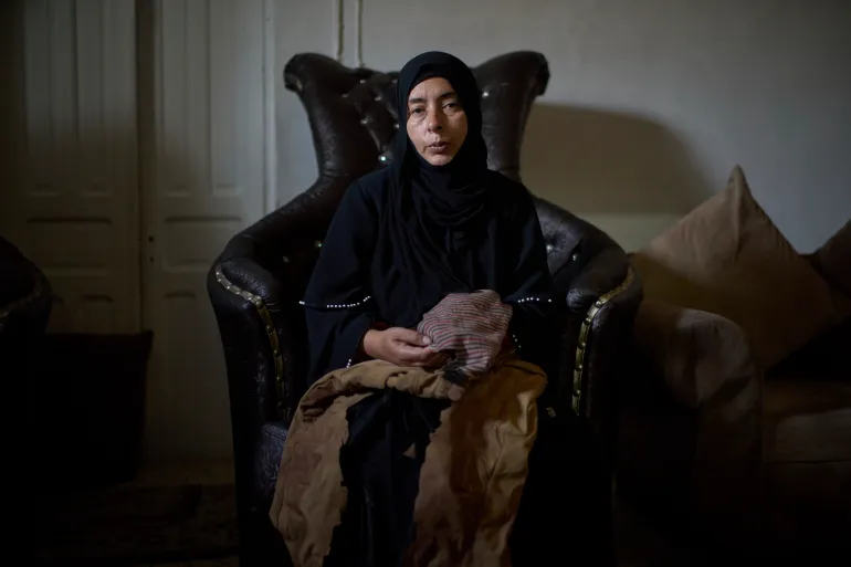 Wafa Jazar holds her 14-year-old son Ahmad's clothes after he was killed by Israeli forces in the West Bank.