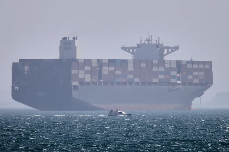 Container ship anchored in the Strait of Hormuz, critical waterway threatened by regional tensions and potential conflict.